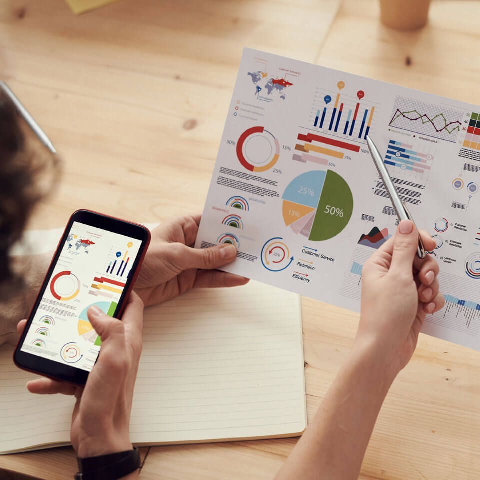 Business owner reviewing printed charts with a phone in hand