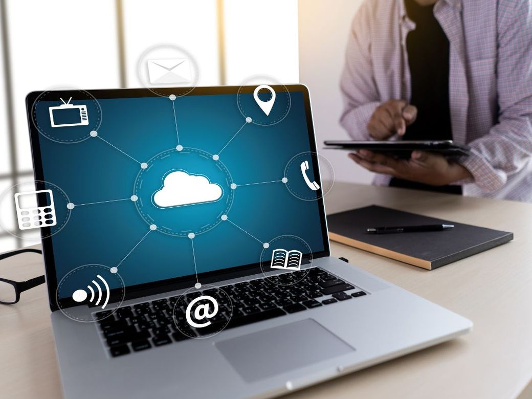 Laptop showing cloud service icons on an office desk