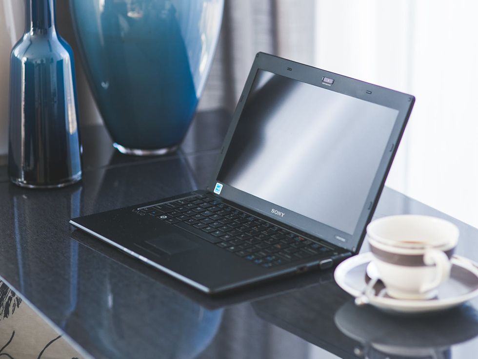 Laptop on an office desk beside a cup of coffee