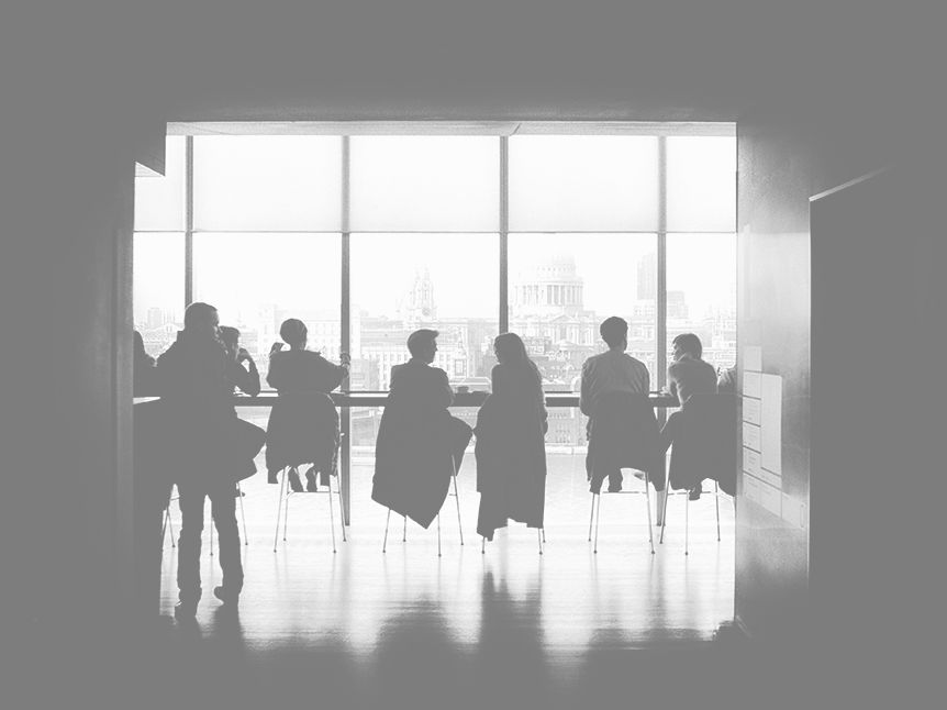 Team meeting around a table in front of bright office windows
