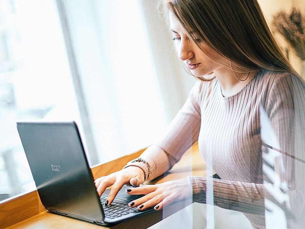 Employee working on a laptop at a bright window desk