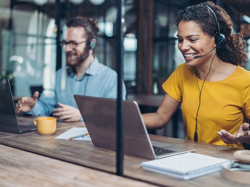 Help desk staff wearing headsets and working at laptops
